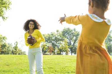 Güzel mutlu Afro-Amerikan aile parkta kaynaşıyor siyahi aile dışarıda eğleniyor, aileler ve çocuklar futbol oynuyor.