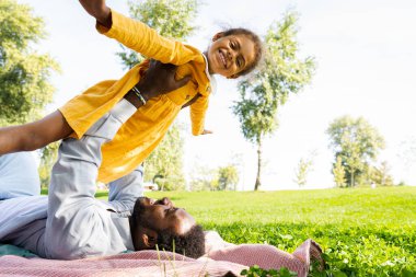 Güzel, mutlu, Afro-Amerikan aile parkta kaynaşıyor, siyahi aile dışarıda eğleniyor, babası tatlı kızıyla oynuyor.