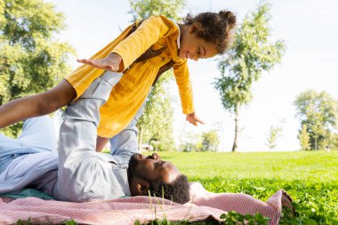 Güzel, mutlu, Afro-Amerikan aile parkta kaynaşıyor, siyahi aile dışarıda eğleniyor, babası tatlı kızıyla oynuyor.