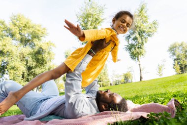 Güzel, mutlu, Afro-Amerikan aile parkta kaynaşıyor, siyahi aile dışarıda eğleniyor, babası tatlı kızıyla oynuyor.