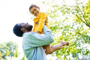 Güzel, mutlu, Afro-Amerikan aile parkta kaynaşıyor, siyahi aile dışarıda eğleniyor, babası tatlı kızıyla oynuyor.