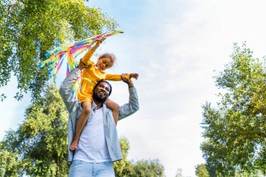 Güzel, mutlu, Afro-Amerikan aile parkta kaynaşıyor, siyahi aile dışarıda eğleniyor, babası tatlı kızıyla oynuyor.