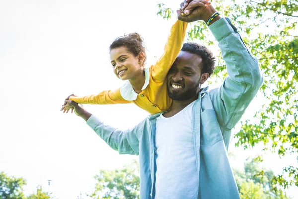 Güzel, mutlu, Afro-Amerikan aile parkta kaynaşıyor, siyahi aile dışarıda eğleniyor, babası tatlı kızıyla oynuyor.