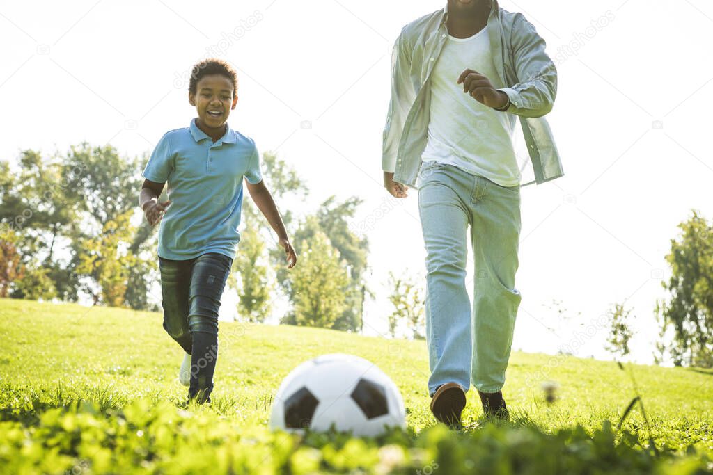 Beautiful happy african american family bonding at the park - Black family having fun outdoors, father and son playing football