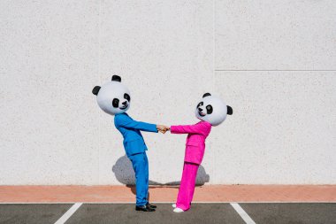 Dev panda kafalı ve renkli takım elbiseli bir çiftin hikaye anlatımı. Kadın ve erkek otoparkta parti yapıyor..