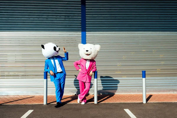 一对夫妇头戴大熊猫头戴彩色西服的故事形象 男人和女人在停车场开派对 — 图库照片