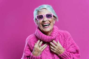 image of a beautiful and elegant old influencer woman. Cool grandmother posing in studio wearing fashionable clothes. Happy senior lady celebrating and making party. Concept about seniority and lifestyle clipart