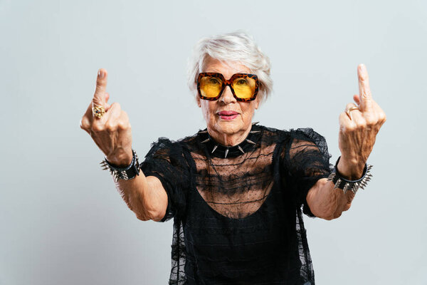 красивая и элегантная старушка. Крутая бабушка позирует в студии в модной одежде. Счастливая старшая леди празднует и устраивает вечеринку. Понятие о старшинстве и образе жизни