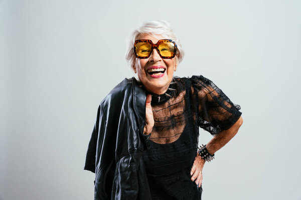 красивая и элегантная старушка. Крутая бабушка позирует в студии в модной одежде. Счастливая старшая леди празднует и устраивает вечеринку. Понятие о старшинстве и образе жизни