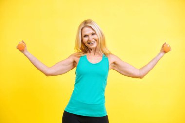 Güzel orta yaşlı kadın spor salonunda spor yapıyor. Renkli arka planlarda fotoşoplama yapan pozitif ve kendini kabullenme konsepti için poz veren son sınıf kadın modeli.