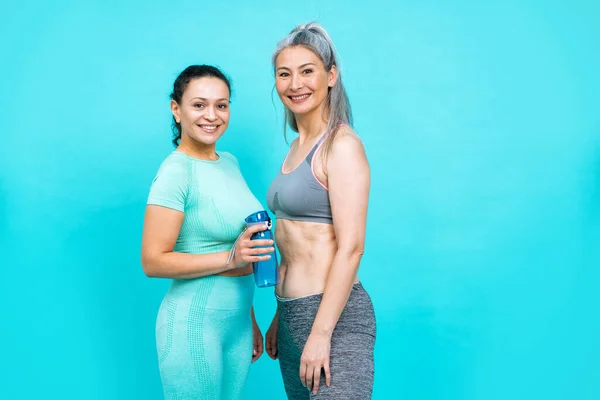 Image of two women with different body, age, and ethnicity making sport. Female models wearing sport outfits having fun at the gym. Concept about body positivity, self acceptance and lifestyle