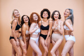krása skupiny žen s různým věkem, pleť a tělo pózují ve studiu pro tělo pozitivní focení. Smíšené ženské modely ve spodním prádle na barevném pozadí