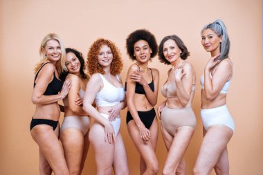 Farklı yaş, ten ve vücutta vücut pozitifliği için poz veren bir grup kadının güzel görüntüsü. Renkli arka planlarda iç çamaşırlı kadın modeller.