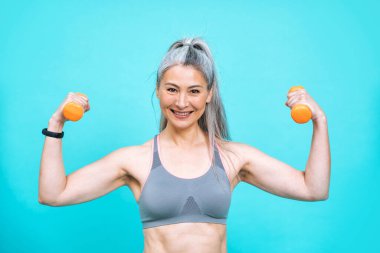 Güzel orta yaşlı kadın spor salonunda spor yapıyor. Beden pozitifliği ve kendini kabullenme konsepti için poz veren kadın model renkli arka planlarda fotoşoplama