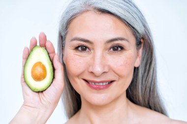 Vücut pozitifliği için stüdyoda poz veren son sınıf bir kadının fotoğrafı. Eski model meyve ve sağlıklı yiyecekler cilt bakımı için iyi gelir.