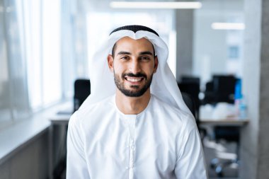 Dubai 'deki ofisinde çalışan yakışıklı bir adam. Geleneksel emirlik beyaz elbiseli başarılı bir iş adamının portreleri. Ortadoğu kültürleri, yaşam tarzı ve meslekleri hakkında kavram