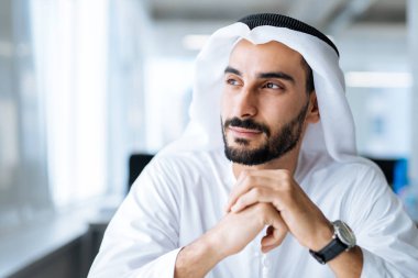 Dubai 'deki ofisinde çalışan yakışıklı bir adam. Geleneksel emirlik beyaz elbiseli başarılı bir iş adamının portreleri. Ortadoğu kültürleri, yaşam tarzı ve meslekleri hakkında kavram