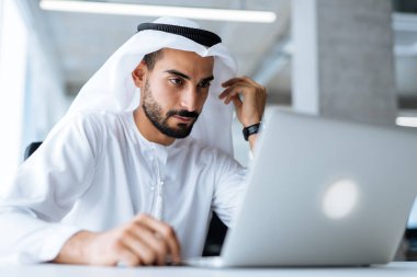 Dubai 'deki ofisinde çalışan yakışıklı bir adam. Geleneksel emirlik beyaz elbiseli başarılı bir iş adamının portreleri. Ortadoğu kültürleri, yaşam tarzı ve meslekleri hakkında kavram