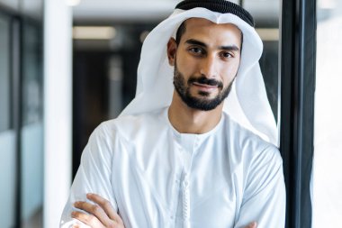 Dubai 'deki ofisinde çalışan yakışıklı bir adam. Geleneksel emirlik beyaz elbiseli başarılı bir iş adamının portreleri. Ortadoğu kültürleri, yaşam tarzı ve meslekleri hakkında kavram