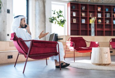 Dubai 'deki ofisinde çalışan yakışıklı bir adam. Geleneksel emirlik beyaz elbiseli başarılı bir iş adamının portreleri. Ortadoğu kültürleri, yaşam tarzı ve meslekleri hakkında kavram