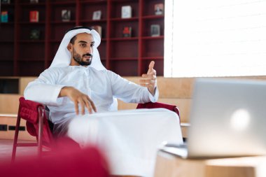 Dubai 'deki ofisinde çalışan yakışıklı bir adam. Geleneksel emirlik beyaz elbiseli başarılı bir iş adamının portreleri. Ortadoğu kültürleri, yaşam tarzı ve meslekleri hakkında kavram