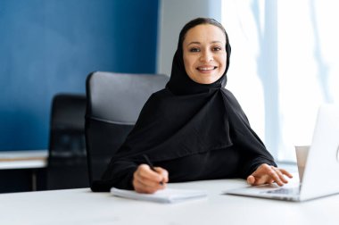 Bilgisayarında çalışan abaya elbiseli güzel bir kadın. Dubai 'de bir iş yerinde orta yaşlı kadın çalışan. Ortadoğu kültürleri ve yaşam tarzı kavramı