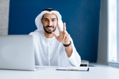 Dubai 'deki ofisinde çalışan yakışıklı bir adam. Geleneksel emirlik beyaz elbiseli başarılı bir iş adamının portreleri. Ortadoğu kültürleri, yaşam tarzı ve meslekleri hakkında kavram