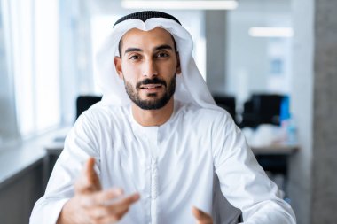 Dubai 'deki ofisinde çalışan yakışıklı bir adam. Geleneksel emirlik beyaz elbiseli başarılı bir iş adamının portreleri. Ortadoğu kültürleri, yaşam tarzı ve meslekleri hakkında kavram