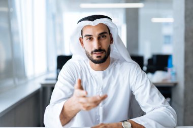 Dubai 'deki ofisinde çalışan yakışıklı bir adam. Geleneksel emirlik beyaz elbiseli başarılı bir iş adamının portreleri. Ortadoğu kültürleri, yaşam tarzı ve meslekleri hakkında kavram