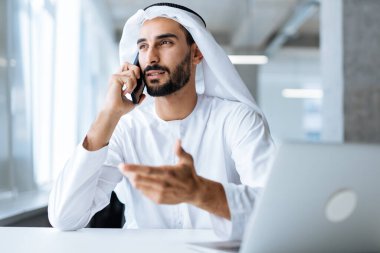 Dubai 'deki ofisinde çalışan yakışıklı bir adam. Geleneksel emirlik beyaz elbiseli başarılı bir iş adamının portreleri. Ortadoğu kültürleri, yaşam tarzı ve meslekleri hakkında kavram