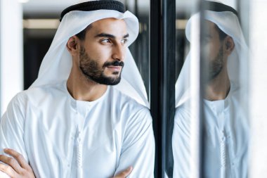 Dubai 'deki ofisinde çalışan yakışıklı bir adam. Geleneksel emirlik beyaz elbiseli başarılı bir iş adamının portreleri. Ortadoğu kültürleri, yaşam tarzı ve meslekleri hakkında kavram