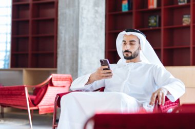 Dubai 'deki ofisinde çalışan yakışıklı bir adam. Geleneksel emirlik beyaz elbiseli başarılı bir iş adamının portreleri. Ortadoğu kültürleri, yaşam tarzı ve meslekleri hakkında kavram