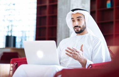 Dubai 'deki ofisinde çalışan yakışıklı bir adam. Geleneksel emirlik beyaz elbiseli başarılı bir iş adamının portreleri. Ortadoğu kültürleri, yaşam tarzı ve meslekleri hakkında kavram
