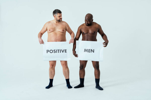 multiethnic men posing for a male edition body positive beauty set showing messages on banners. Shirtless guys with different age, and body wearing boxers underwear