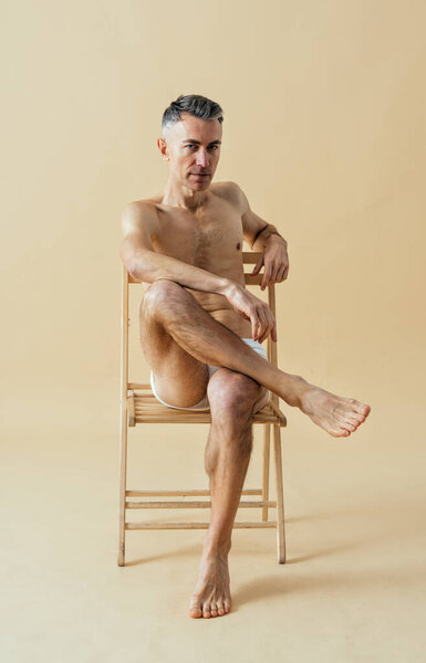 man posing for a male edition body positive beauty set. Shirtless guy wearing boxers underwear in studio