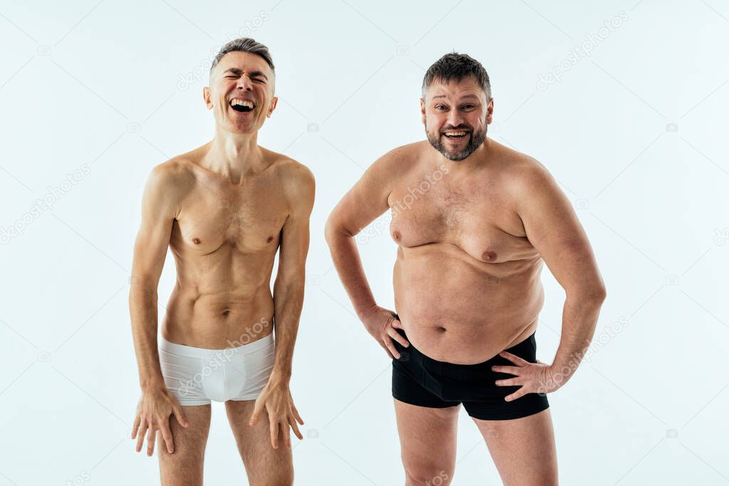 Two multiethnic men posing for a male edition body positive beauty set. Shirtless guys with different age, and body wearing boxers underwear