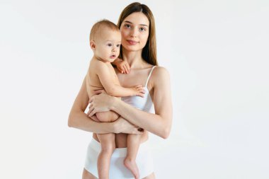 Bebeğini renkli arka planda tutan mutlu bir kadın - iç çamaşırı giyen genç bir kadın - hamilelik, annelik, insanlar ve beklenti konsepti