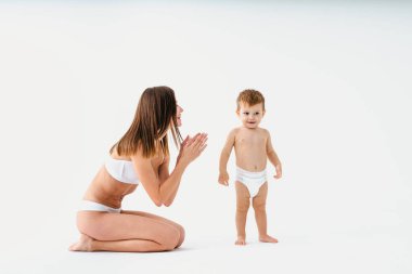 Bebeğini renkli arka planda tutan mutlu bir kadın - iç çamaşırı giyen genç bir kadın - hamilelik, annelik, insanlar ve beklenti konsepti