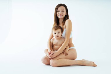 Bebeğini renkli arka planda tutan mutlu bir kadın - iç çamaşırı giyen genç bir kadın - hamilelik, annelik, insanlar ve beklenti konsepti