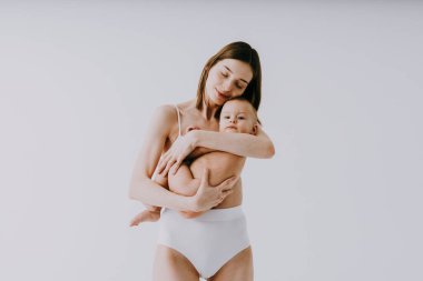 Bebeğini renkli arka planda tutan mutlu bir kadın - iç çamaşırı giyen genç bir kadın - hamilelik, annelik, insanlar ve beklenti konsepti