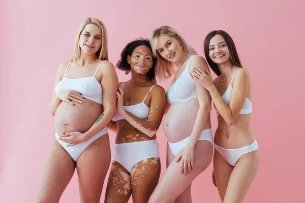 Happy pregnant women with big bellies and beautiful mothers posing in studio - Multiracial group of positive pregnant women and moms wearing underwear - Pregnancy, motherhood, people, body positive and body acceptance concept