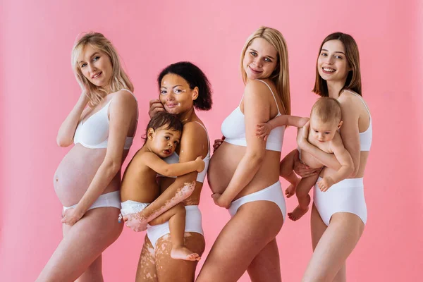 Premium Photo  Happy women holding their babies on colored background -  young women wearing underwear taking care of their little sons - pregnancy,  motherhood, people and expectation concept