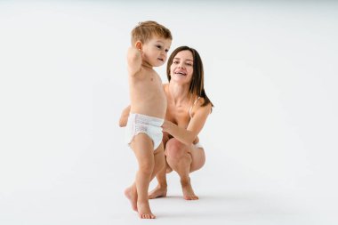 Bebeğini renkli arka planda tutan mutlu bir kadın - iç çamaşırı giyen genç bir kadın - hamilelik, annelik, insanlar ve beklenti konsepti