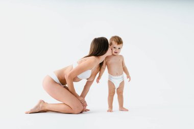 Bebeğini renkli arka planda tutan mutlu bir kadın - iç çamaşırı giyen genç bir kadın - hamilelik, annelik, insanlar ve beklenti konsepti