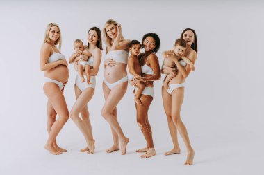 Büyük göbekli mutlu hamile kadınlar ve stüdyoda bebekleri olan güzel anneler - çok ırklı hamile kadınlar ve iç çamaşırı giyen anneler - hamilelik, annelik, insanlar, vücut pozitifliği ve vücut kabulü kavramı