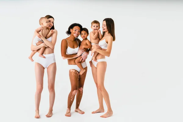 在有色人种背景下养育孩子的多民族快乐妇女 穿着内衣照顾小儿子的年轻妇女 体形阳性和体格接纳的概念 — 图库照片