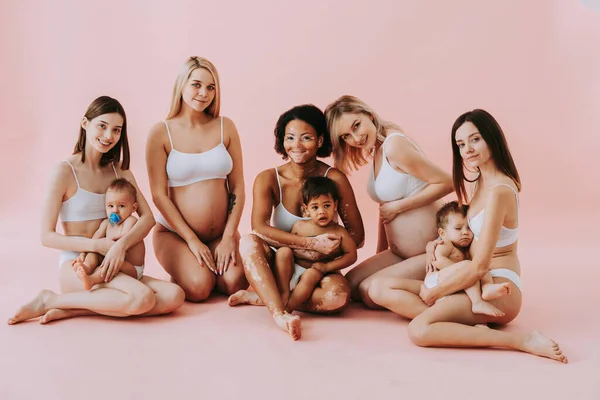 Premium Photo  Happy women holding their babies on colored background -  young women wearing underwear taking care of their little sons - pregnancy,  motherhood, people and expectation concept