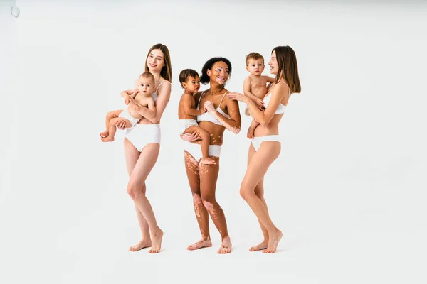 Szczęśliwe Wielonarodowe Kobiety Trzymające Swoje Dzieci Kolorowym Tle Młode Kobiety — Zdjęcie stockowe
