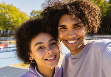 Interracial young couple dating outdoors, colored and modern urban background - Multiethnic people with stylish and cool urban clothes bonding outdoors clipart