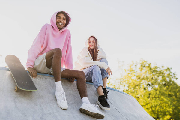 Multicultural group of young friends bonding outdoors and having fun - Stylish cool teens gathering at urban skate park